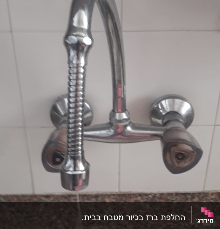 ברז מתכת עם ידית כפולה על קיר קרמיקה